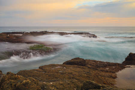 Long exposure of rocks in waves, giving a mist like effect over ocean in Laguna Beach, Californiaの写真素材
