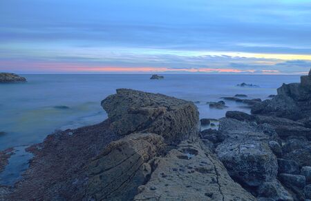 Long exposure of sunset over rocks, giving a mist like effect over ocean in Laguna Beach, California, United Statesの写真素材