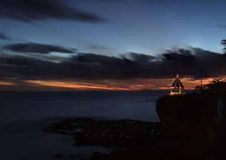 A gazebo on a cliff overlooking the ocean in Laguna Beach, California, lit with Christmas lights at sunset.の写真素材