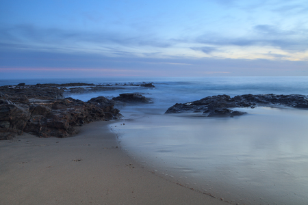 Long exposure of sunset over rocks, giving a mist like effect over ocean in Laguna Beach, California, United Statesの写真素材