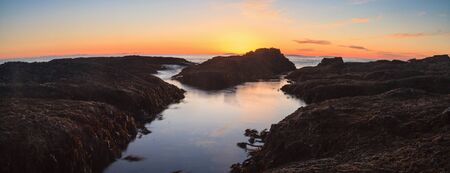 Long exposure of sunset over rocks, giving a mist like effect over ocean in Laguna Beach, California, United Statesの写真素材