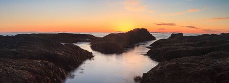 Long exposure of sunset over rocks, giving a mist like effect over ocean in Laguna Beach, California, United Statesの写真素材