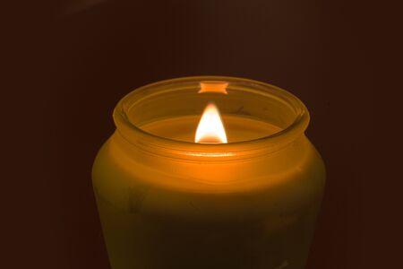 A candle glows in the dark, providing a room with low, romantic lightの写真素材