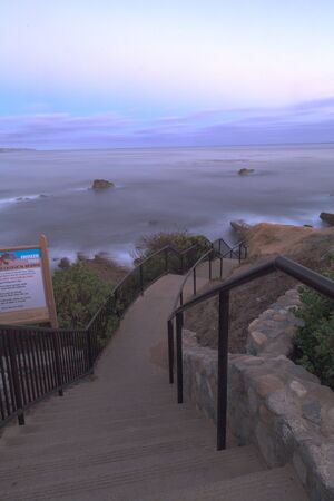 Steps from Heisler Park leading down to the sand and ocean in Laguna Beach, California at sunset.