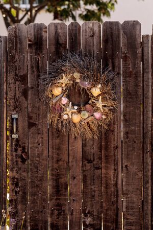 Seashell, starfish, heather and urchin wreath on a rustic wooden door backgroundの写真素材