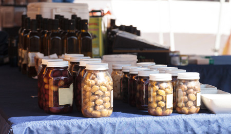 Jars of colorful olives grown and pickled in Southern California and displayed at a farmers market.の写真素材