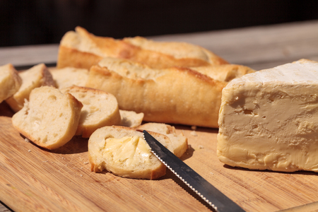 French bread and triple cream brie cheese on a cutting board with a knife.の写真素材