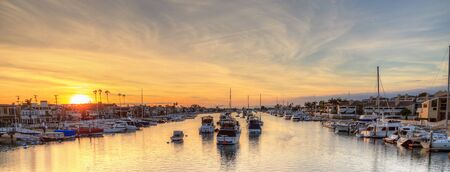 Balboa Island harbor at sunset with ships and sailboats visible from the bridge that leads into Balboa Island, Southern California, USAの写真素材