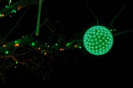 Background of colorful holiday green and white lights with balls and icicles on a tree at Christmas.の写真素材