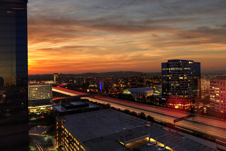 Sunrise over light trails and city lights on a highway in Irvine, California, USA.の写真素材
