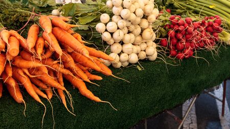 Red beets, orange carrots, and white and red radishes at an organic farmers marketの写真素材