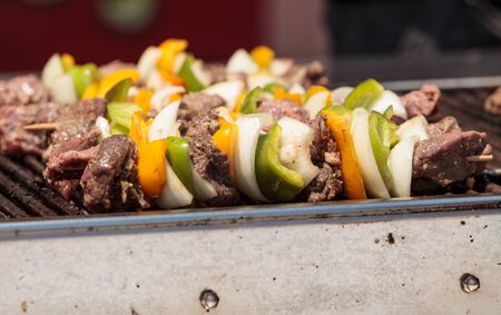 Chicken, beef and onion kabobs on a barbecue grill cooking at a fair ground.の写真素材