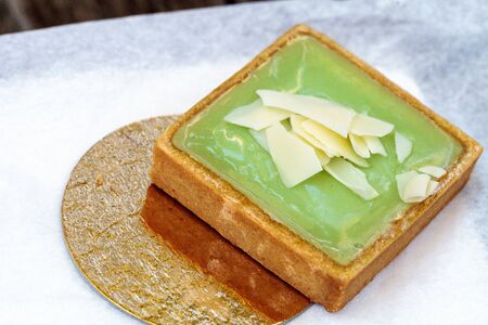 Green Keylime tart pastry with a cookie crust and white chocolate flakes in bakery.の写真素材