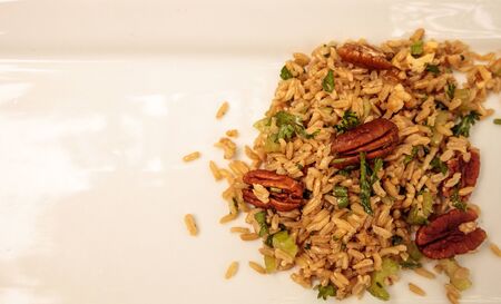 Healthy pecan nut brown rice with cilantro and spices on a white plateの写真素材