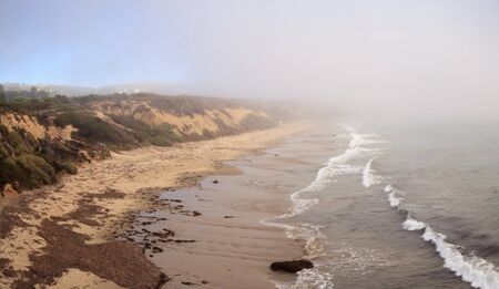 Fog drifts in over the ocean at Crystal Cove state beach on the edge of Laguna Beach and Corona del Mar, California in fall.の写真素材