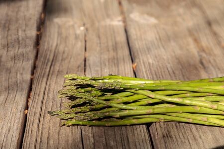 Fresh thin asparagus on the rustic wood background of an old farm table in autumn.の写真素材