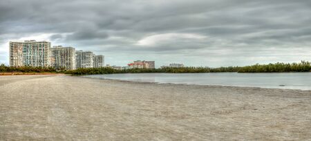 Buildings in the distance on Marco Island, Florida, beach under an overcast sky in winterの写真素材