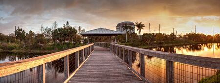 Sunset over Gazebo on a wooden secluded, tranquil boardwalk along a marsh pond in Freedom Park in Naples, Floridaのeditorial素材