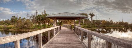Sunset over Gazebo on a wooden secluded, tranquil boardwalk along a marsh pond in Freedom Park in Naples, Floridaの写真素材