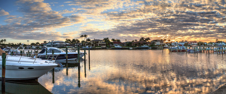Harbor with boats at golden hour as day breaks over the North Gulf Shore Harbor along the Village at Venetian Bay at sunrise in Naples Florida.の写真素材