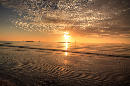 Ripples of waves under a sunset sky of red and orange at South Marco Island Beach in Floridaの写真素材