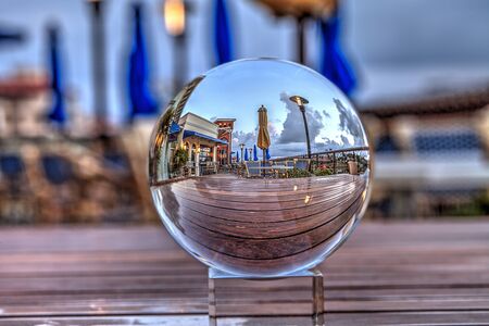 Outdoor dining through a crystal ball at the Village at Venetian Bay at sunrise in Naples, Florida.の写真素材