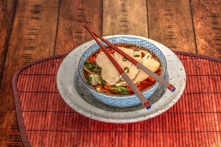Asian chicken noodle soup with chopsticks and beer.