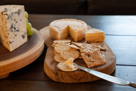 Cheese plate and wine including chardonnay, gourmet crackers, a washed rind soft cheese, a raw milk...