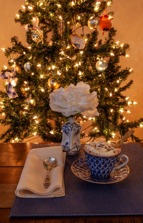 Hot chocolate and layered dark and white chocolate dessert on a fancy bone China plate tipped with gold and a silver spoon in front of a Christmas tree.の写真素材