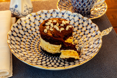 Layered dark and white chocolate dessert on a fancy bone China plate tipped with gold and a silver spoon.の写真素材