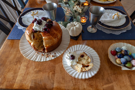 Panettone bread with cherries and whipped cream on a holiday table at Christmas.