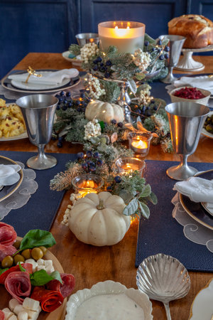 Festive candles and greenery on a table with fine bone China and a silver serving spoon at Christmas.の写真素材