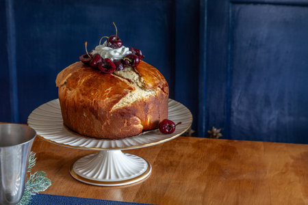 Panettone bread with cherries and whipped cream on a holiday table at Christmas.