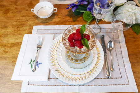 Fresh raspberries in a compote of gold and crystal on a place setting on an Easter table.