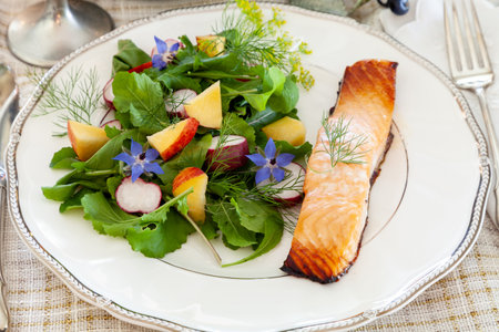Organic greens salad with purple borage flowers, arugula, radish and salmon on a fine China dish with elegant silverware.の写真素材