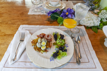 Quail eggs on a hashbrown potato nest with prosciutto and decorative fruit.