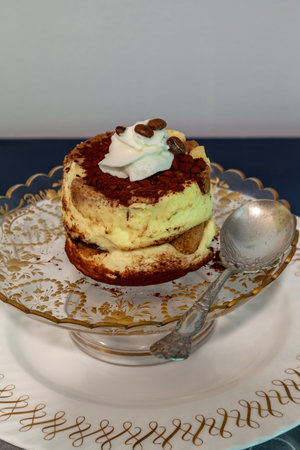 Tiramisu with whipped cream and coffee beans on a gold etched antique compote.の写真素材