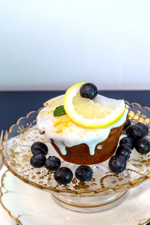 Lemon loaf with zest icing and blueberries on a gold etched antique compote.の写真素材
