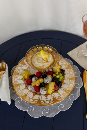 Fancy fruit salad with dragon fruit, star fruit, raspberries, blackberries, and kiwi on a gold encrusted plate with Greek yogurt.の写真素材