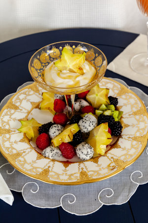 Fancy fruit salad with dragon fruit, star fruit, raspberries, blackberries, and kiwi on a gold encrusted plate with yogurt.の写真素材