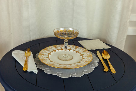 Gold encrusted plate, a gold compote, utensils, and a linen napkin and placemat.の写真素材
