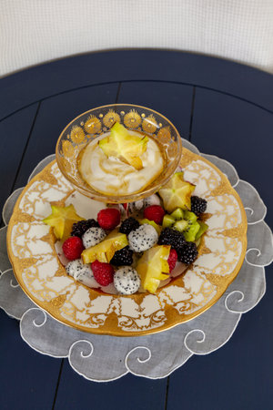 Fancy fruit salad with dragon fruit, star fruit, raspberries, blackberries, and kiwi on a gold encrusted plate with Greek yogurt.の写真素材