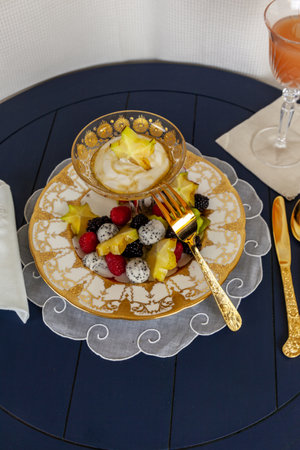 Fancy fruit salad with dragon fruit, star fruit, raspberries, blackberries, and kiwi on a gold encrusted plate with Greek yogurt.の写真素材