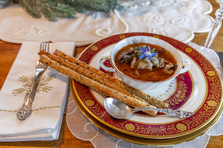 Duck stew and bread sticks on fine China place settings on a Christmas table.の写真素材