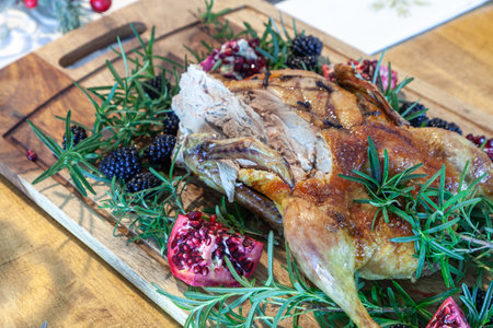Christmas goose on a bed of rosemary with blackberries and pomegranate fruit on a cutting board.の写真素材