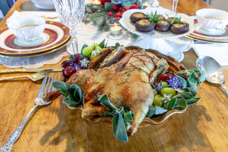 Roasted duck on a platter with sage leaves and grapes on a formal table setting at Christmas.の写真素材