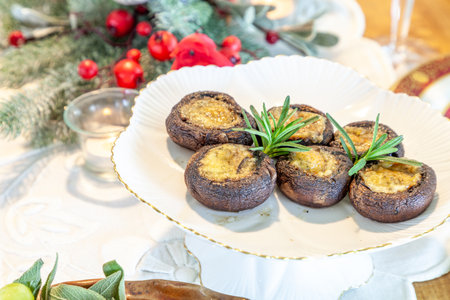 Mushroom caps stuffed with cheese, bacon and breading on an elevated plate across a holiday table.の写真素材