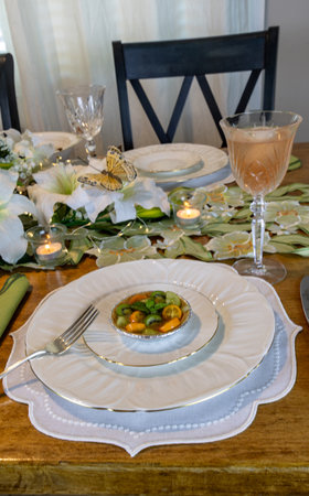 Green kiwi berry, grape and kumquat tart with passion fruit curd on a cookie crust on a fine China plate and silverware.の写真素材
