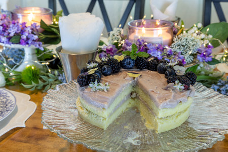 Chantilly Cake with blackberries and blueberries over a light blackberry frosting on a fancy gourmet table with a spring lilac table setting.の写真素材