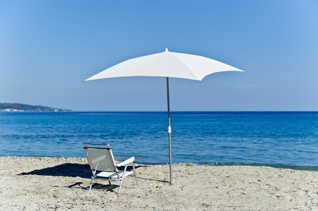 White chair with the white beach umbrella on the mediterranean coastの写真素材